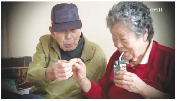 최근 요양보호사 자격시험에 합격한 최대식 할아버지(왼쪽)와 치매 초기인 부인 김현정 할머니. 직접 사온 과자를 부인에게 건네고 있다.(사진 KBS 화면 캡쳐)